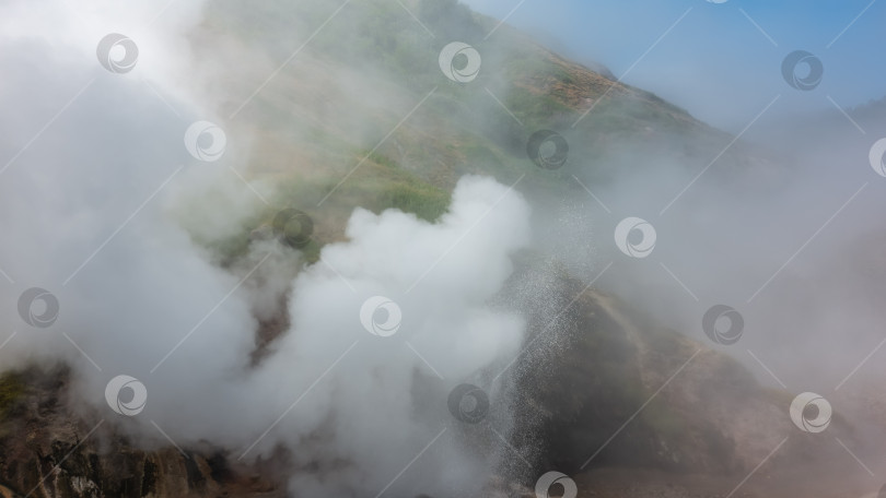 Скачать Склон холма окутан густым паром от извергающегося гейзера. фотосток Ozero