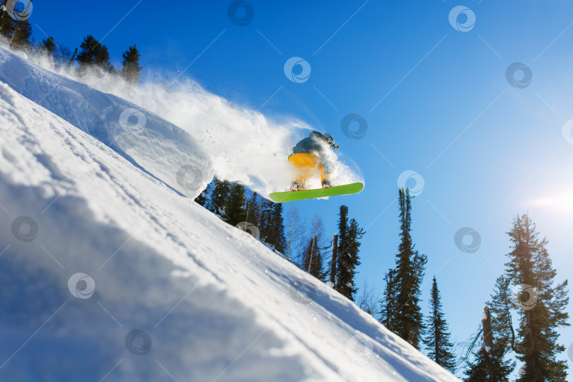 Скачать Сноубордист во время прыжка в высоких горах в солнечный день. фотосток Ozero