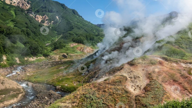 Скачать Столбы пара из горячих источников поднимаются над склоном холма. фотосток Ozero