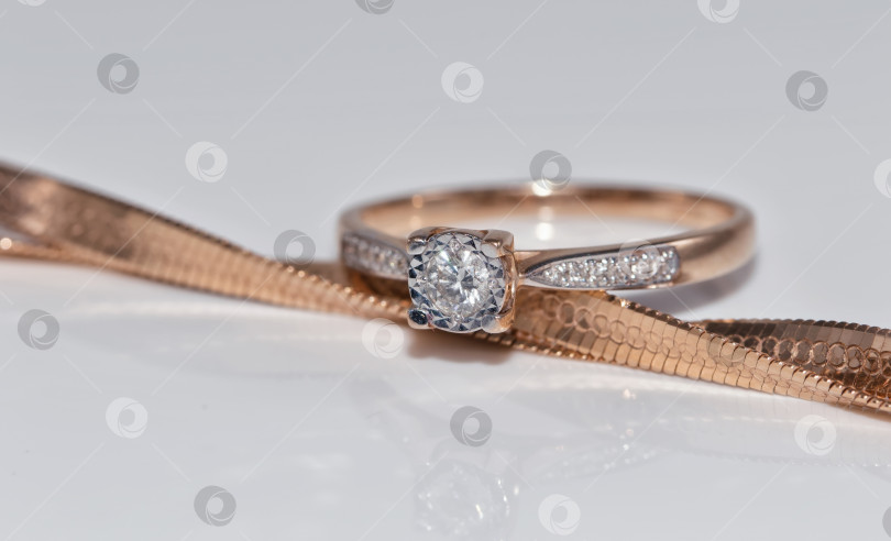 Скачать Тонкое элегантное золотое кольцо с бриллиантом и золотой цепочкой фотосток Ozero