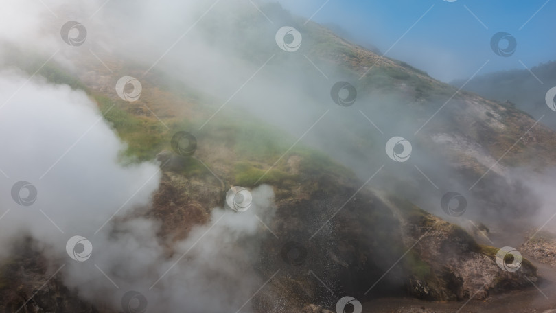 Скачать Склон холма окутан густым паром от извергающегося гейзера. фотосток Ozero