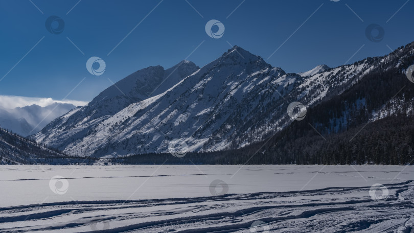 Скачать Замерзшее и заснеженное озеро окружено горами. фотосток Ozero