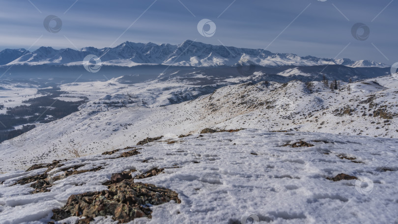 Скачать На заснеженном высокогорном плато видны следы ног и каменистая почва. фотосток Ozero