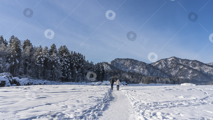 Скачать Два человека уходят по тропинке, протоптанной в снегу. фотосток Ozero