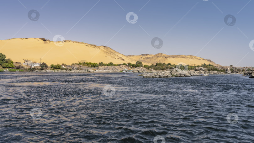 Скачать На берегу реки видны живописные валуны, пришвартован туристический катер. фотосток Ozero