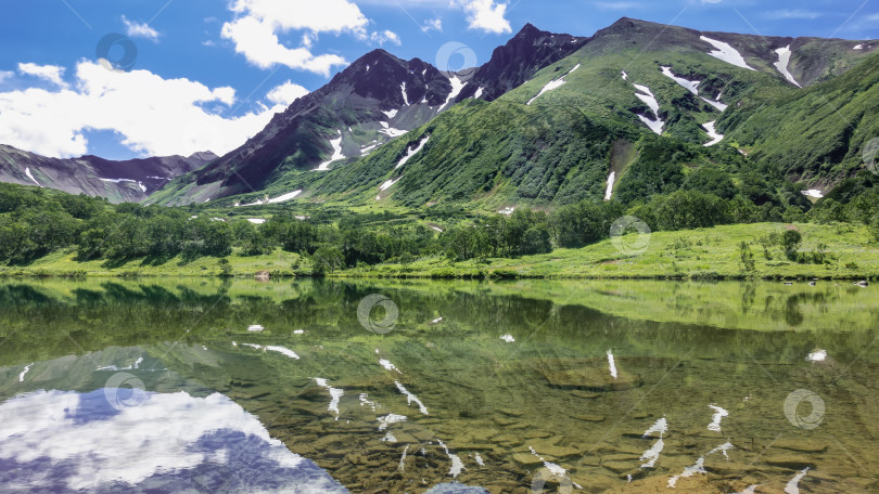 Скачать Спокойное альпийское озеро. Камни на дне видны сквозь прозрачную воду. фотосток Ozero
