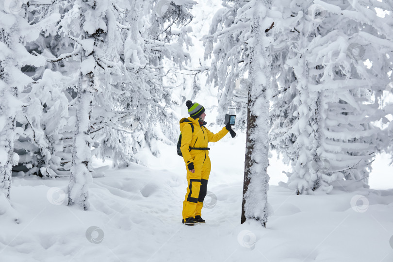 Скачать женщина-путешественница в зимнем лесу записывает видео на смартфон фотосток Ozero