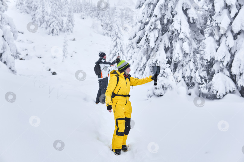 Скачать пара путешественников в зимнем горном лесу делает селфи. фотосток Ozero