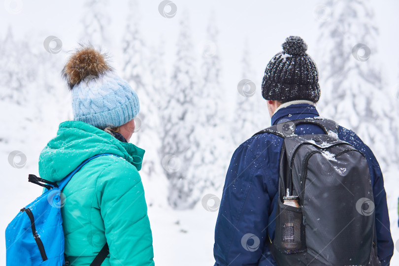 Скачать мужчина и женщина с рюкзаками смотрят на зимний лесной пейзаж фотосток Ozero