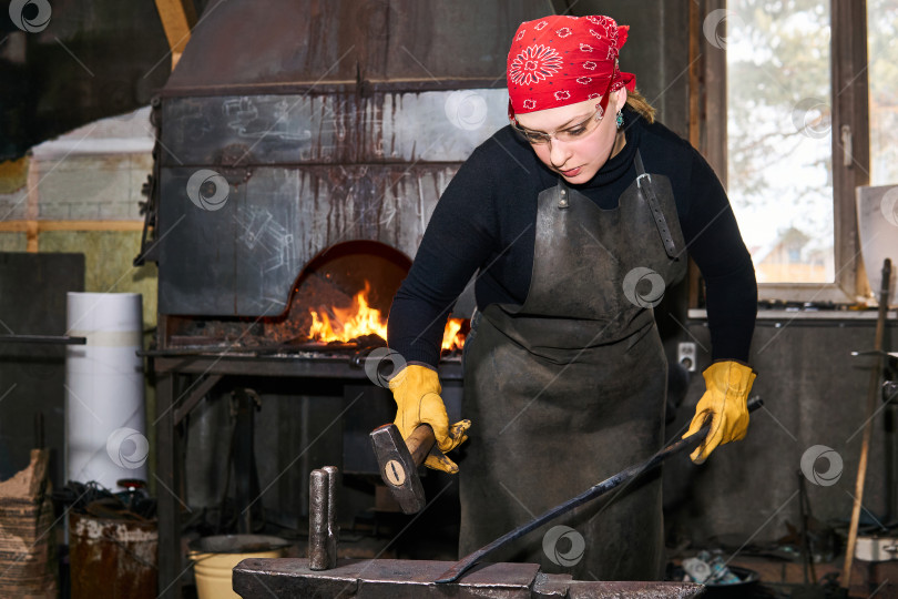 Скачать женщина-кузнец, мастер по металлу, кует горячую металлическую заготовку на фотосток Ozero
