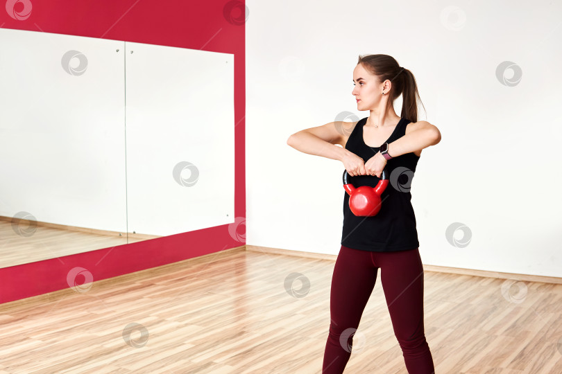 Скачать молодая женщина тренируется с гирями в тренажерном зале, глядя в зеркало фотосток Ozero