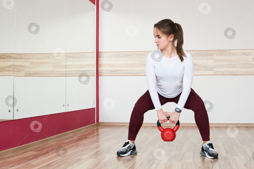 Скачать молодая женщина тренируется с гирями в тренажерном зале, глядя в зеркало фотосток Ozero