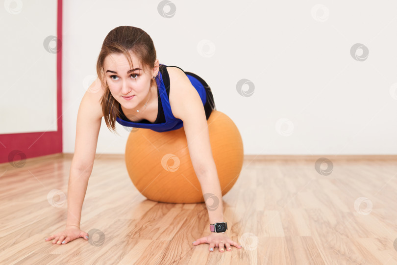 Скачать молодая женщина тренируется, отжимаясь с мячом для упражнений в g фотосток Ozero