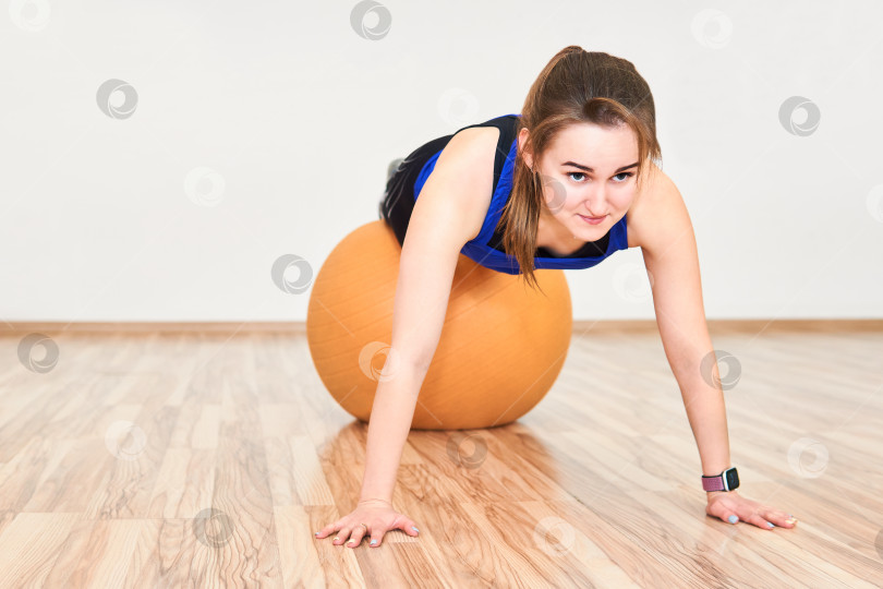 Скачать молодая женщина тренируется, отжимаясь с мячом для йоги в тренажерном зале фотосток Ozero