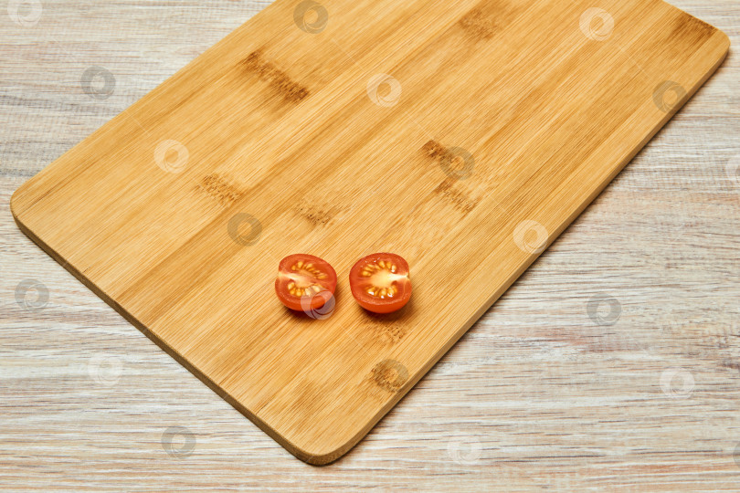 Скачать разрезанный пополам маленький помидор черри выложите на разделочную доску на столе фотосток Ozero