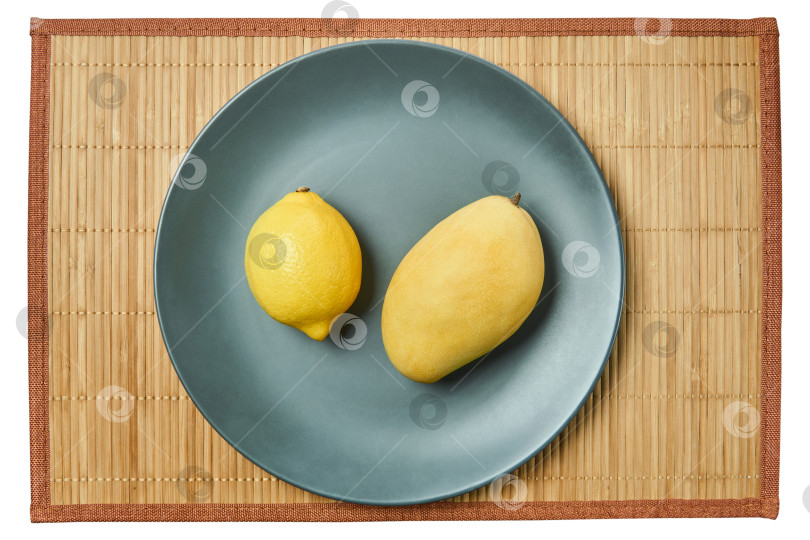 Скачать яркий лимон и желтое манго на серой тарелке на тростниковой скатерти фотосток Ozero