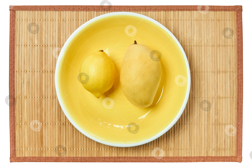 Скачать яркий лимон и бледное манго на желтой тарелке на тростниковой скатерти фотосток Ozero