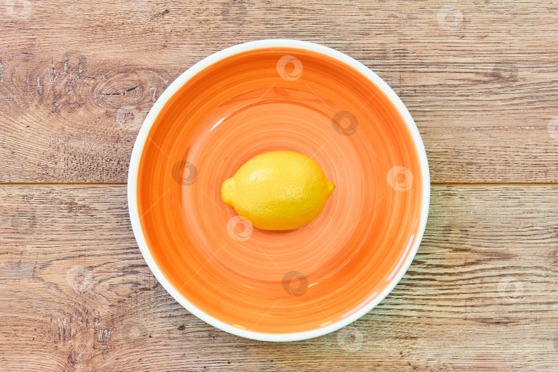 Скачать желтый лимон на оранжевой тарелке на деревянной столешнице фотосток Ozero