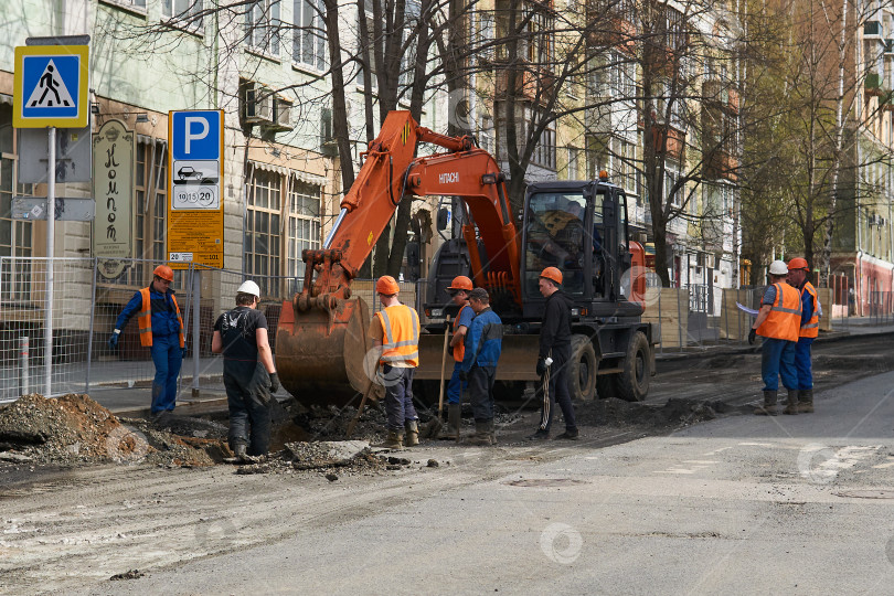 Скачать рабочие собрались вокруг экскаватора, обсуждая работы по рытью траншей. фотосток Ozero