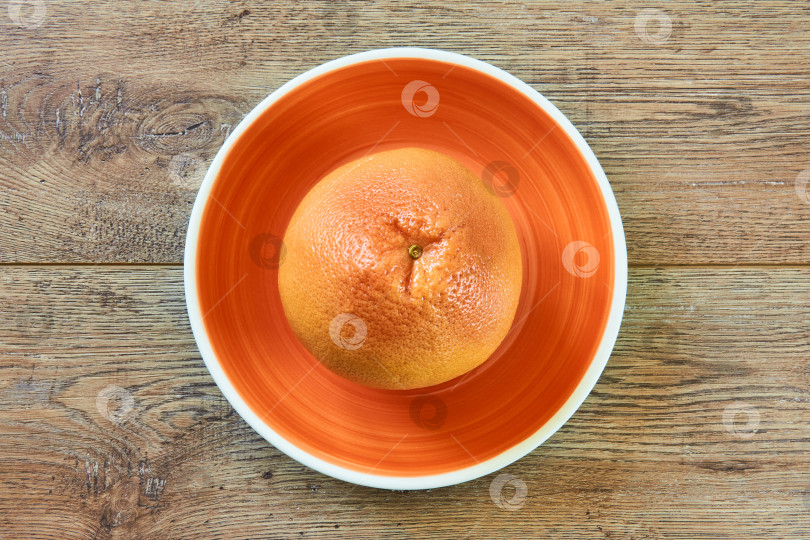 Скачать розовато-желтый грейпфрут на оранжевой тарелке на тростниковой скатерти фотосток Ozero
