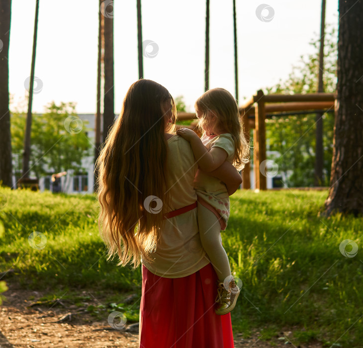 Скачать мать взяла свою дочь на руки во время прогулки по городскому парку фотосток Ozero