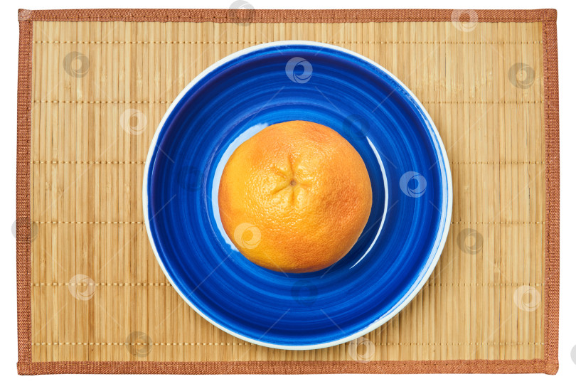 Скачать розово-желтый грейпфрут на голубой тарелке на тростниковом коврике фотосток Ozero