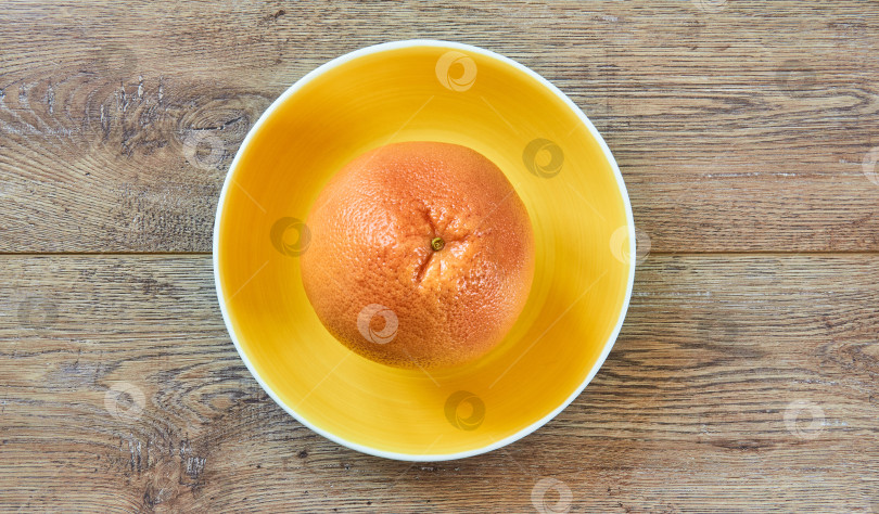 Скачать бледно-оранжевый грейпфрут на желтой тарелке на тростниковой скатерти фотосток Ozero