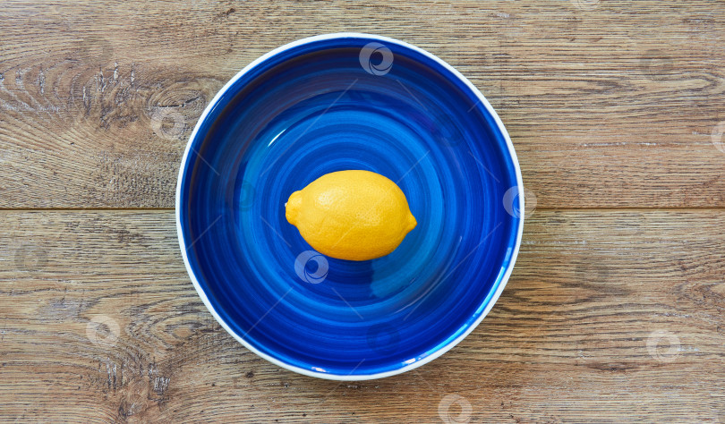 Скачать ярко-желтый лимон на синей тарелке на деревянной столешнице фотосток Ozero