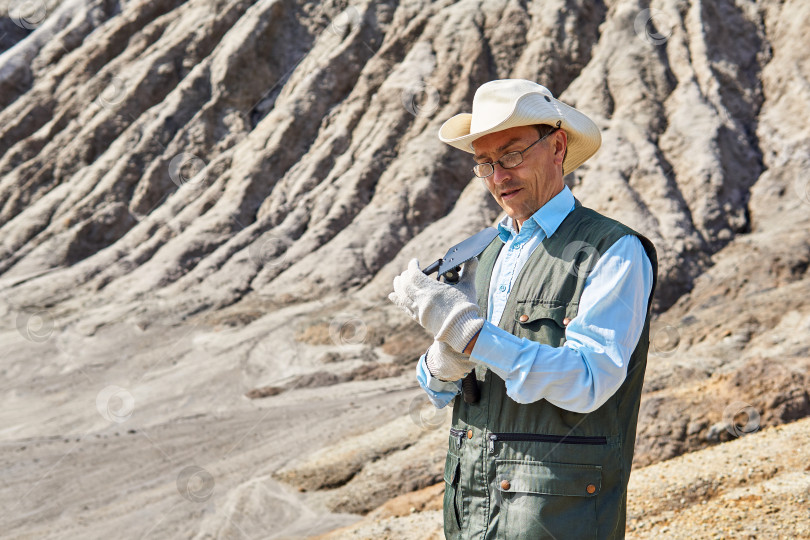 Скачать мужчина-исследователь в пустыне рассматривает складную лопату фотосток Ozero