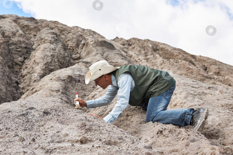 Скачать мужчина-археолог чистит находку щеткой в пустыне фотосток Ozero