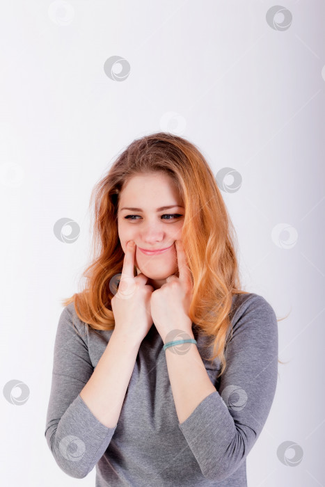 Скачать красивая молодая женщина принуждает себя улыбнуться, прижимая пальцы к губам фотосток Ozero