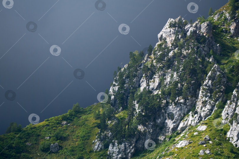 Скачать горный пейзаж - скала, освещенная солнцем, и мрачное облако. фотосток Ozero