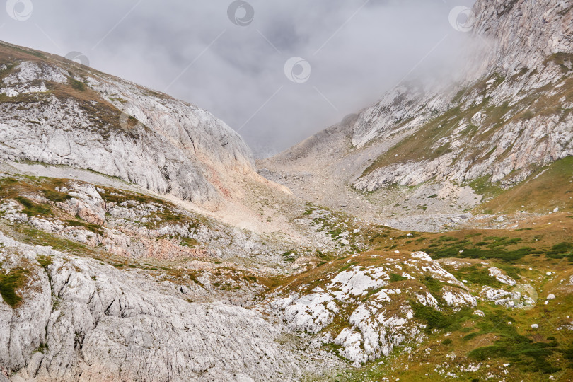 Скачать скалистое альпийское ущелье, частично скрытое облаком фотосток Ozero