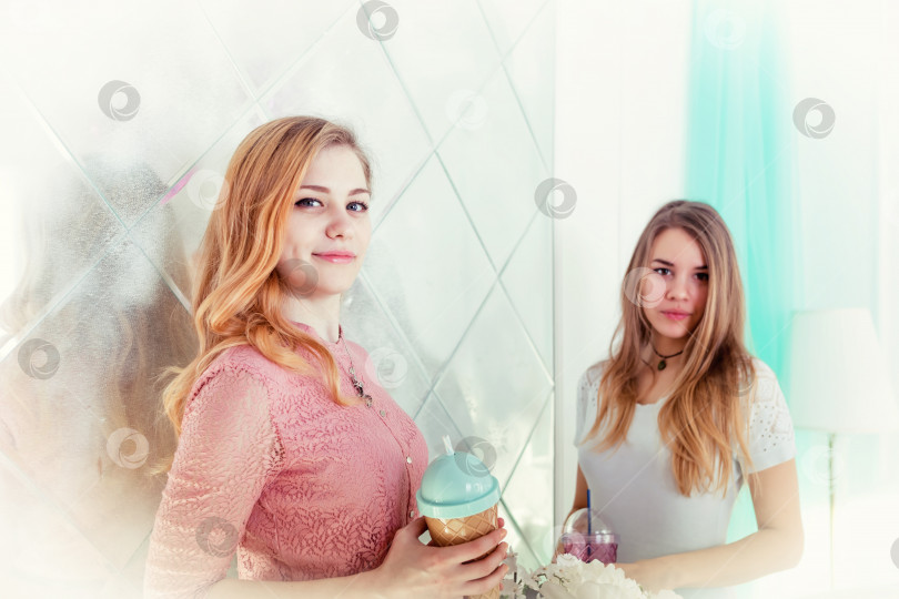 Скачать Две симпатичные девушки в платьях пьют напитки из чашек с крышками и трубочками фотосток Ozero