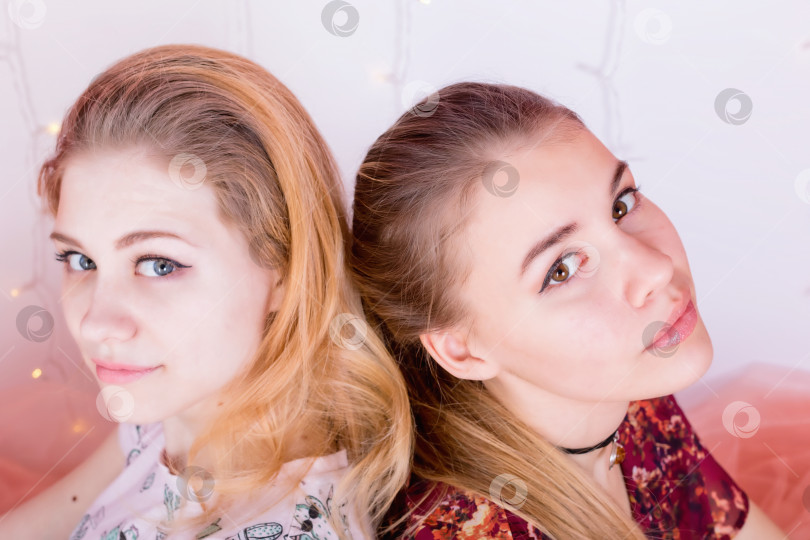 Скачать портрет двух симпатичных девушек, сидящих в позе спина к спине фотосток Ozero