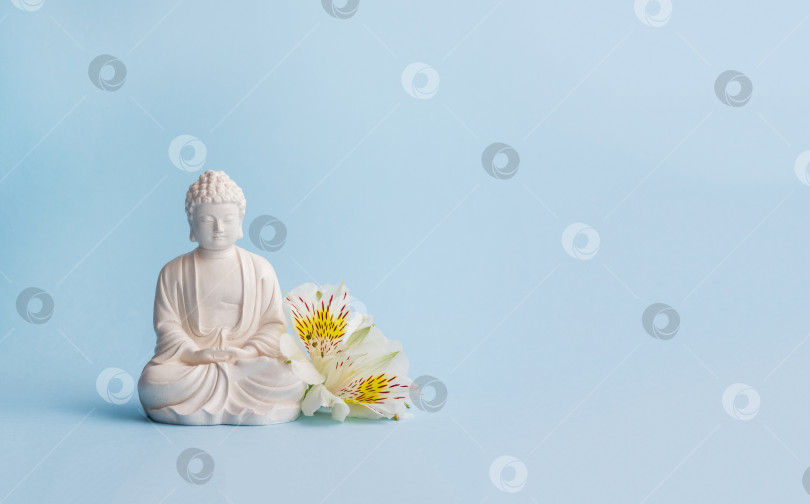Скачать Статуэтка Будды и цветы. Праздник буддизма Весак. Ментальное здоровье и медитация фотосток Ozero