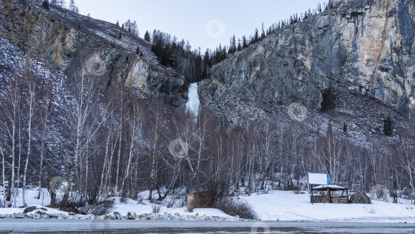 Скачать В ущелье между горными склонами виден замерзший водопад. фотосток Ozero