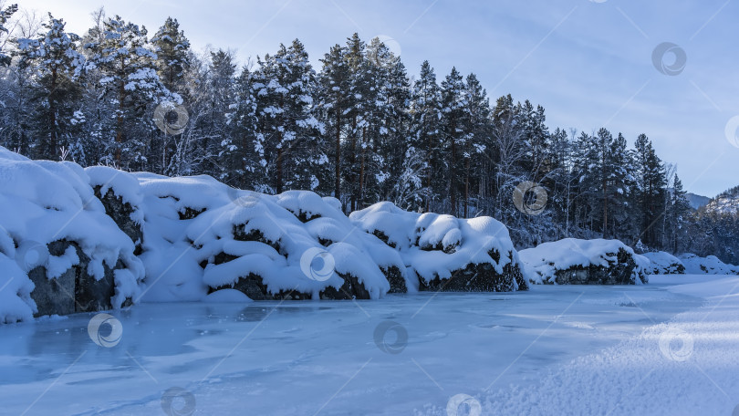 Скачать Живописные валуны на берегу замерзшей реки покрыты слоями снега. фотосток Ozero