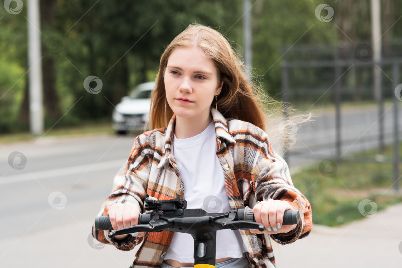 Скачать молодая женщина на электрическом скутере едет по улице фотосток Ozero