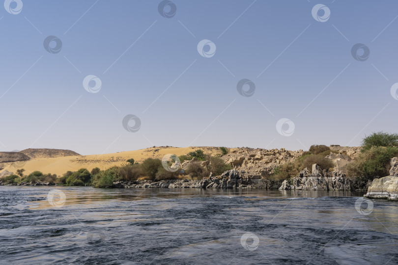 Скачать Вдоль берега реки видны живописные валуны и зеленая растительность. фотосток Ozero