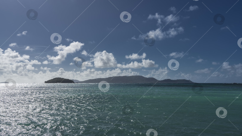 Скачать Силуэты тропических островов на фоне голубого неба и белых облаков. фотосток Ozero