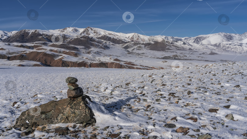 Скачать Пирамида из камней построена на заснеженном высокогорном плато. фотосток Ozero