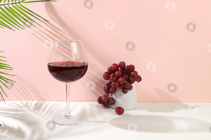 Скачать Современный натюрморт с красным вином, алкогольным коктейлем "Маргарита" и виноградом на пастельном фоне с длинными резкими тенями, минималистичная концепция для бара фотосток Ozero