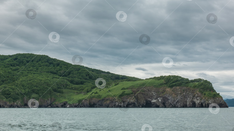 Скачать Живописное побережье Камчатки на фоне пасмурного неба и океана. фотосток Ozero