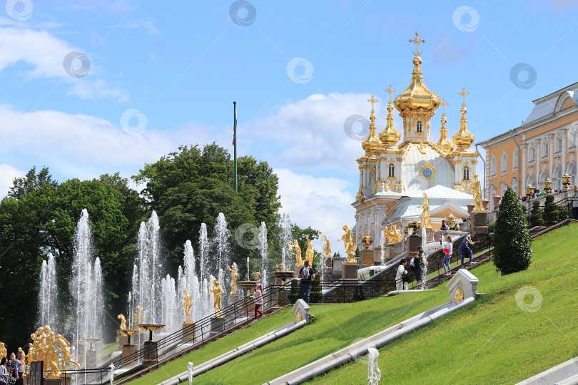 Скачать Россия, Санкт-Петербург, Петергоф, 12 июля 2021 года. На фотографии изображен фонтан Большого каскада в Нижнем парке Государственного музея-заповедника "Петергоф" и скульптуры крупным планом в брызгах воды фотосток Ozero