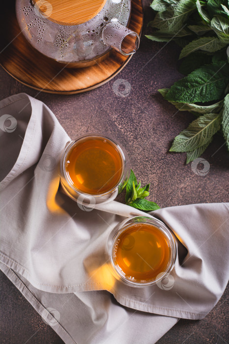 Скачать Успокаивающий зеленый мятный чай в чашках и заварочном чайнике на столешнице и в фотосток Ozero