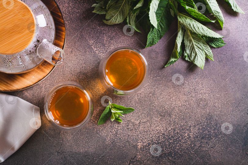 Скачать Свежий мятный чай в чашках и заварочном чайнике с листьями на столешнице vi фотосток Ozero