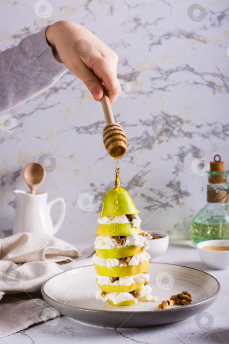 Скачать Рука поливает грушу слоем меда с рикоттой и грецкими орехами фотосток Ozero