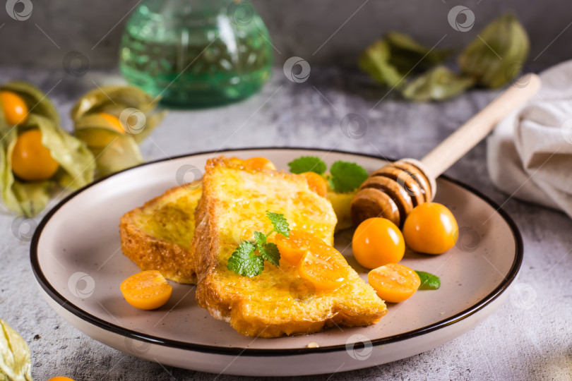 Скачать Тосты, обжаренные в яйце с физалисом, медом и мятой, выложите на тарелку. Хом фотосток Ozero