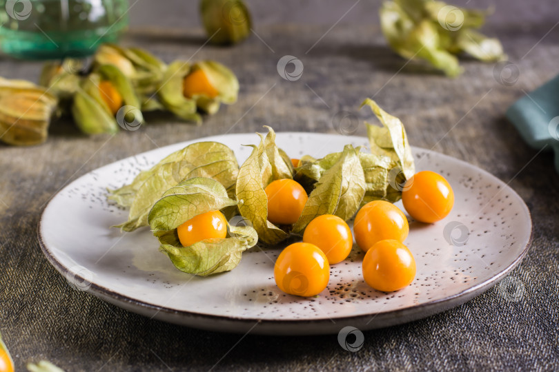 Скачать Спелые плоды физалиса на тарелке. Органическая вегетарианская пища. фотосток Ozero